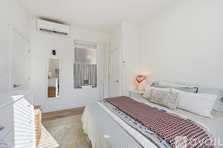 A bedroom with a large bed and a window with curtains.