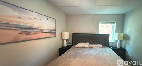 A bedroom with a large bed and a painting on the wall.