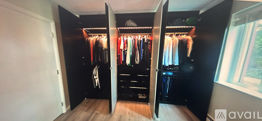 A black wardrobe with clothes hanging on hangers.