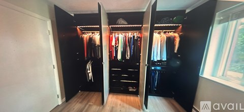 A black wardrobe with clothes hanging on hangers.