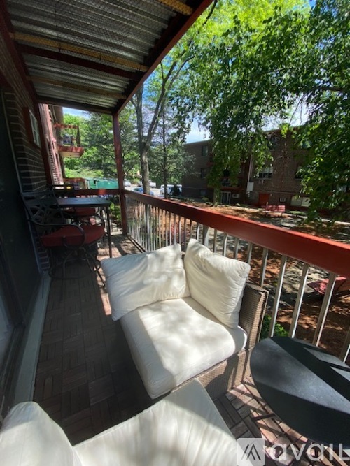 A white couch is on a balcony with a view of a building.