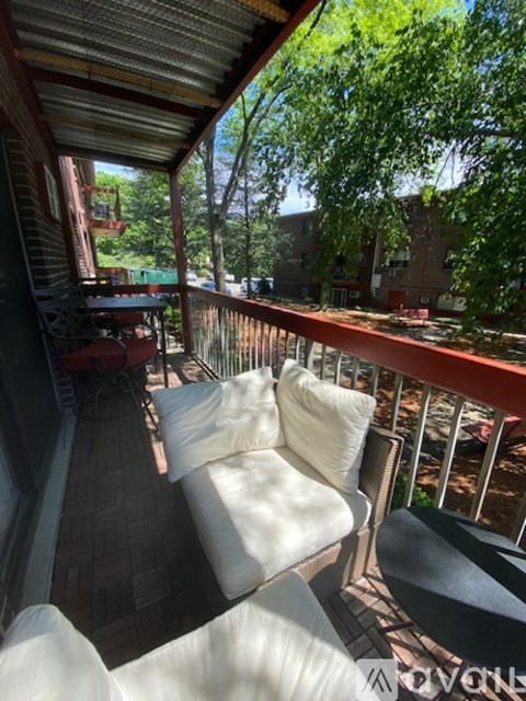 A white couch is on a balcony with a view of a building.