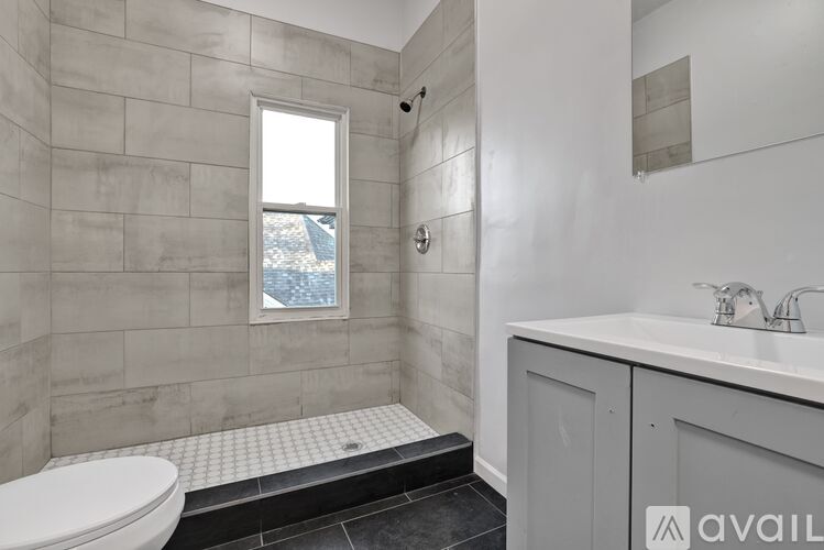 A bathroom with a toilet, sink, and a window.