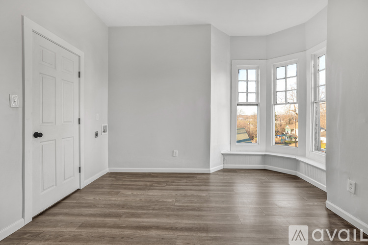 A spacious room with wooden flooring and white walls.