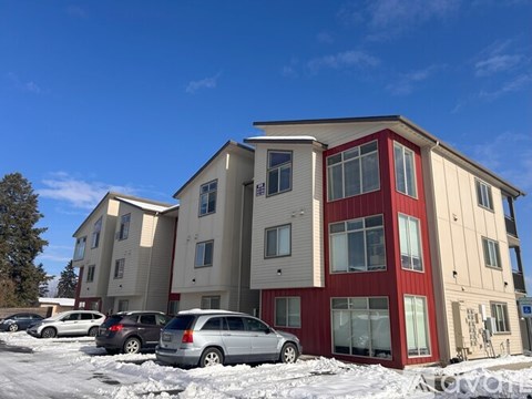 Apartment building with cars parked in front.