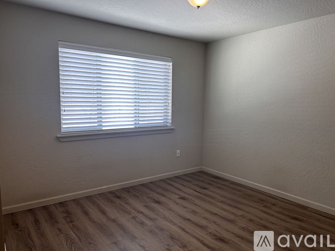 A room with a window covered by white blinds.