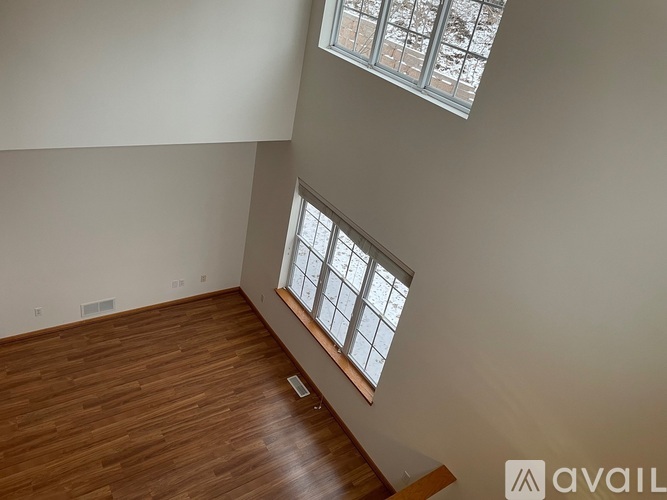 A room with wooden flooring and a window with a view of trees.