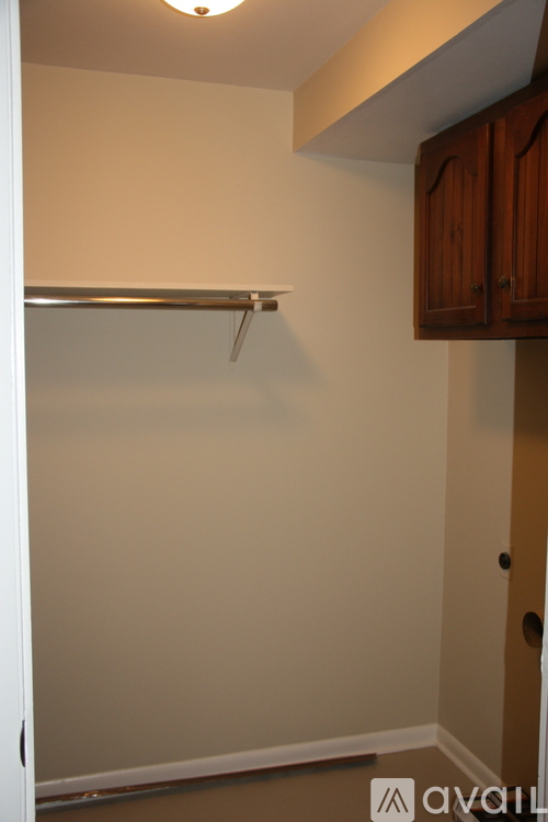 A white closet with a shelf and a white door.