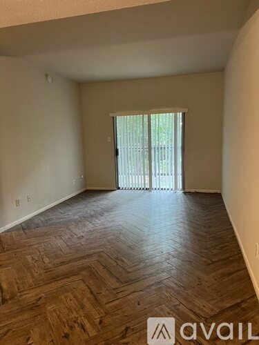 A room with wooden flooring and a window with blinds.