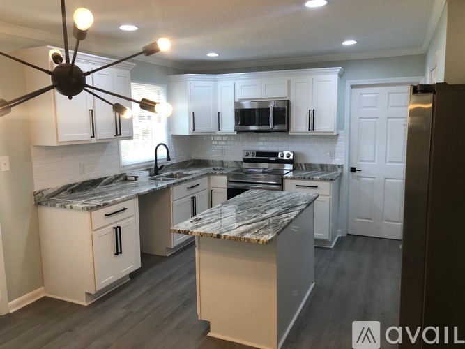 A modern kitchen with a marble countertop and white cabinets.