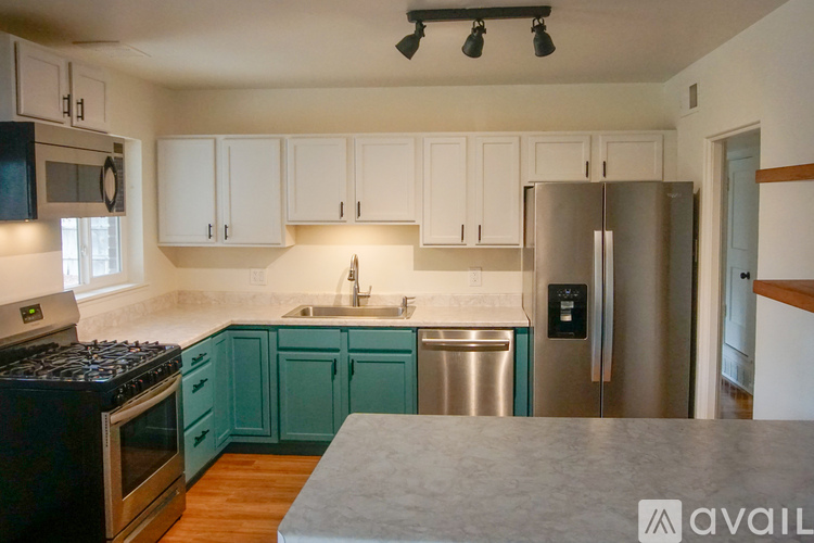 A kitchen with a black stove top oven and a stainless steel refrigerator.