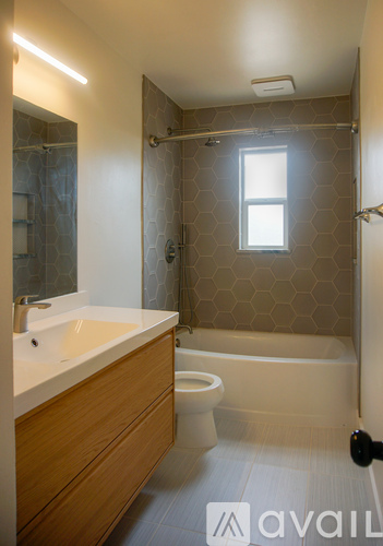 A bathroom with a white sink and a window in the shower.