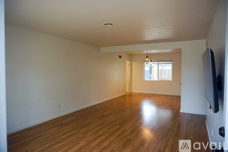 A spacious room with wooden floors and a television on the wall.