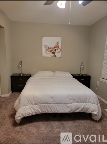 A bedroom with a white bed and a painting on the wall.