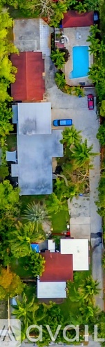 A bird's eye view of a house with a red roof and a blue swimming pool surrounded by greenery.