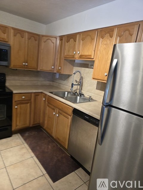 A kitchen with wooden cabinets and a stainless steel refrigerator.