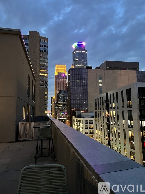 A cityscape at dusk with a building illuminated in rainbow colors.