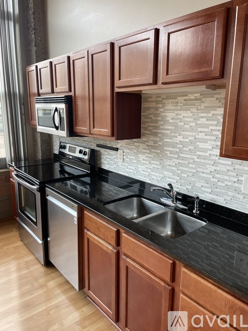 A kitchen with brown cabinets and a black countertop.