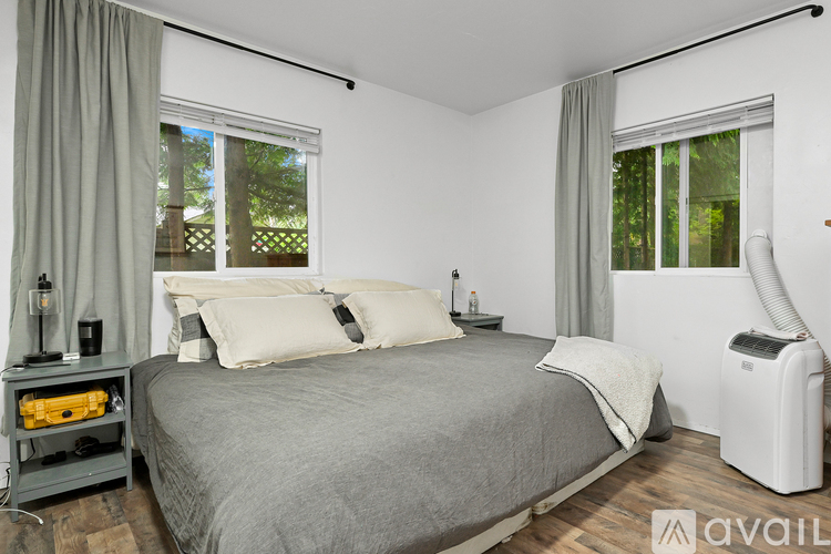 A bedroom with a bed, nightstand, and window with curtains.