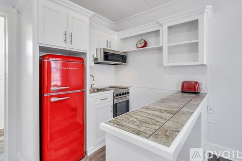 A red fridge in a kitchen with a microwave above it.