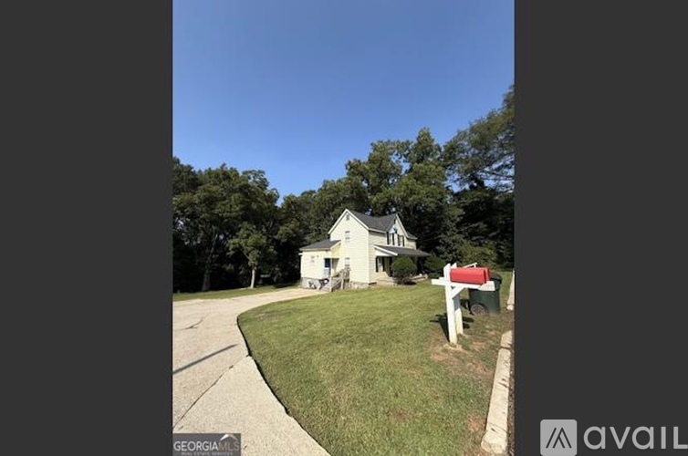 A white house with a red mailbox is for sale.