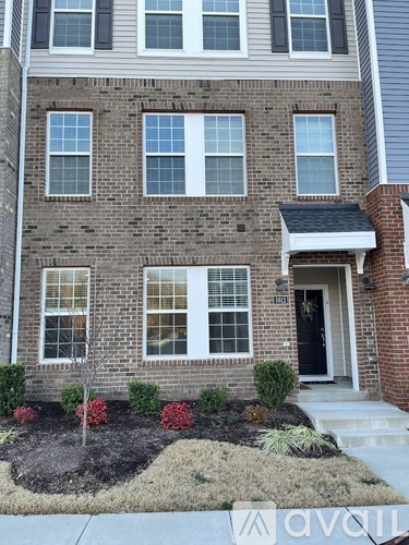 A brick house with a front yard and a black door.