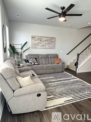 A living room with a grey couch and a rug.