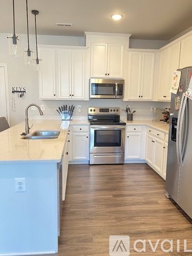 A kitchen with white cabinets and a wooden floor.