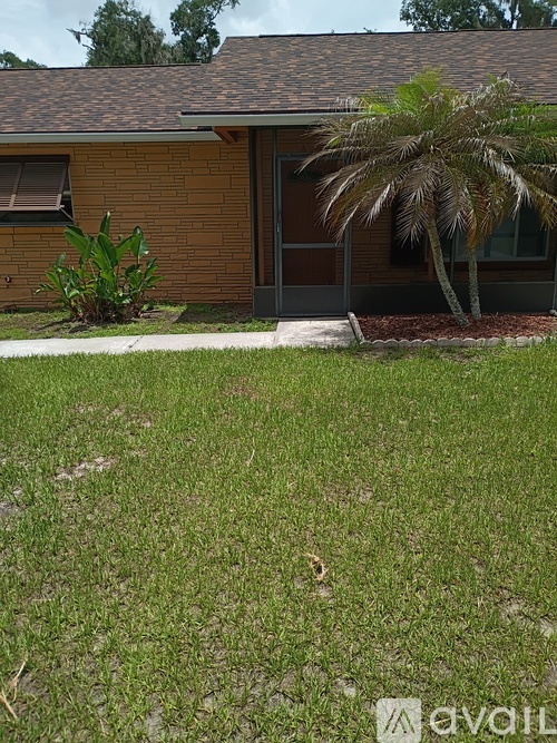 A house with a brown brick exterior and a palm tree in front.