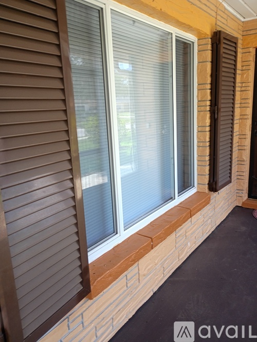 A window with blinds and a wall with a brick pattern.