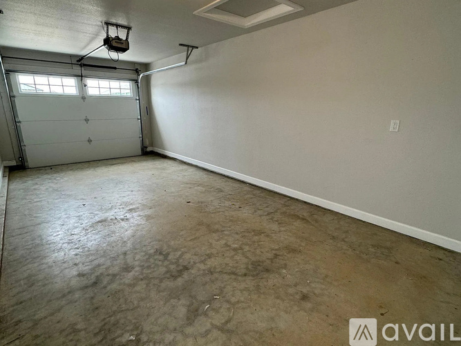 A spacious garage with a concrete floor and a white wall.