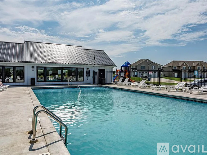 A swimming pool with a slide and lounge chairs in front of a building.