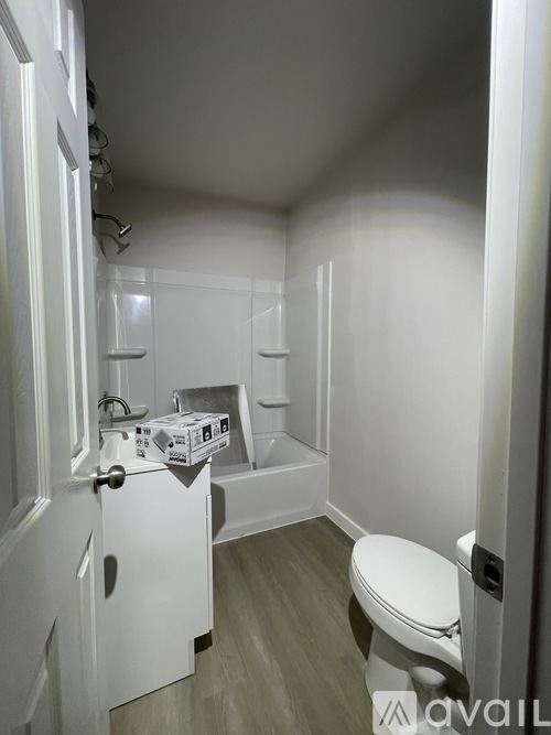 A white toilet sits in a small bathroom with a white cabinet and a white door.