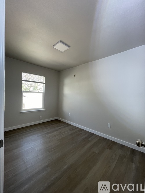 A room with a window and wooden flooring.