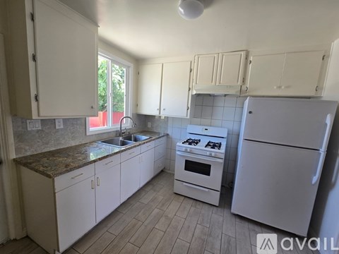 A kitchen with white cabinets and appliances.