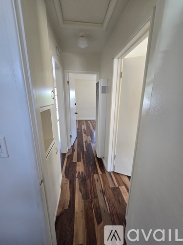 A hallway with a wooden floor and white walls.