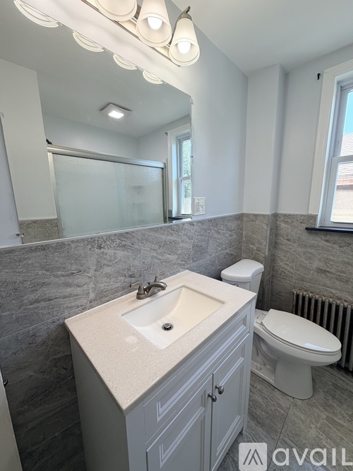 A bathroom with a sink, toilet, and a mirror.
