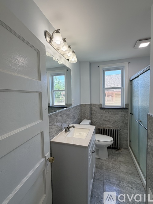 A bathroom with a toilet, sink, and a window.