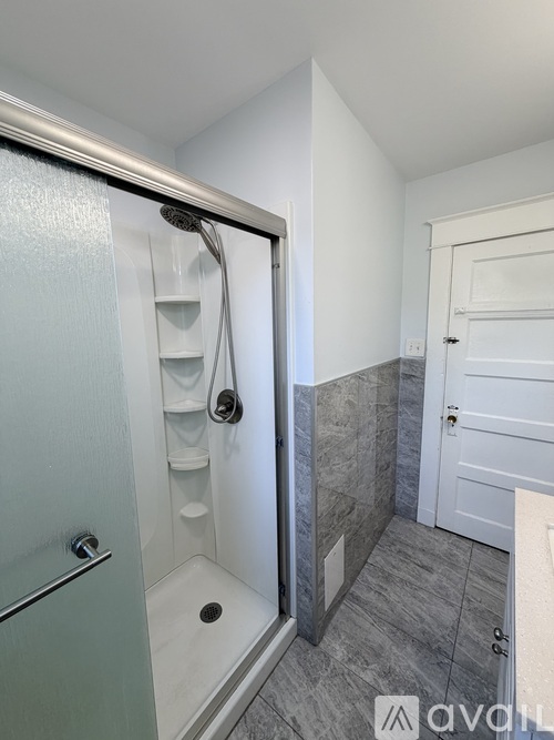A bathroom with a walk-in shower and a white door.