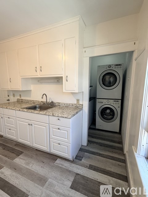 A kitchen with white cabinets and a washing machine in the doorway.