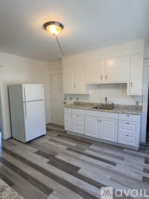 A kitchen with white cabinets and a refrigerator.