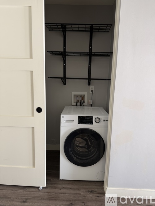 A white washing machine is in a small laundry room.