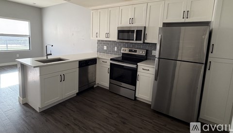A kitchen with white cabinets and a stainless steel refrigerator.