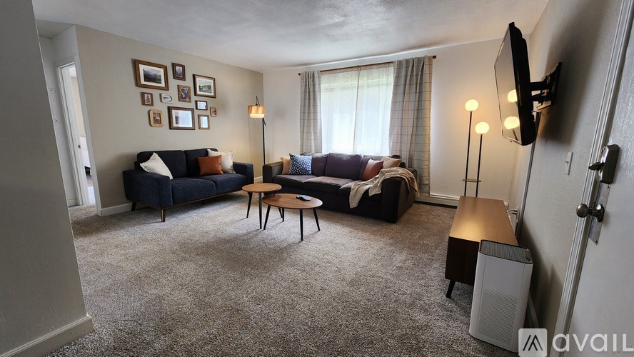 A living room with a couch, a chair, a coffee table, and a television.