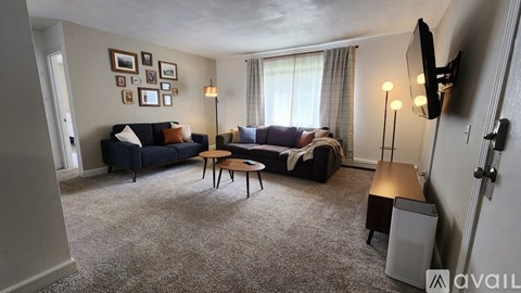 A living room with a couch, a chair, a coffee table, and a television.