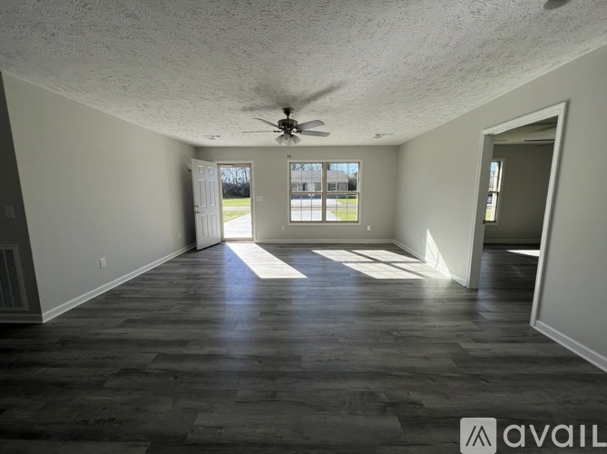 A spacious room with a ceiling fan and large windows.