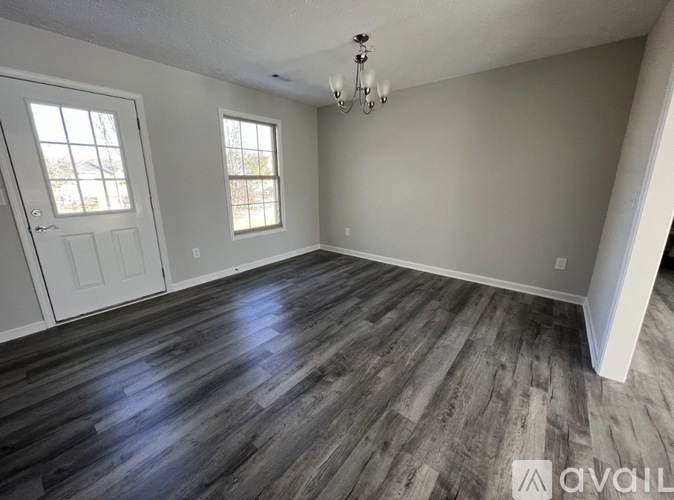 A room with wooden flooring and a chandelier.