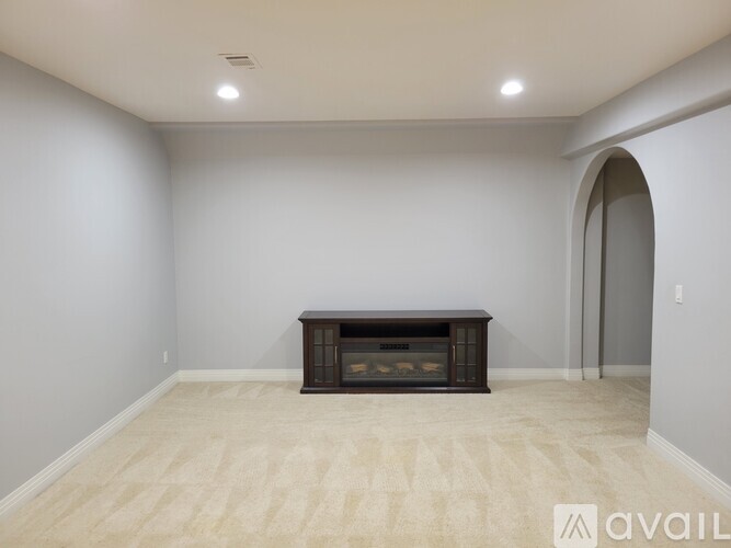 A spacious room with a fireplace and a carpeted floor.