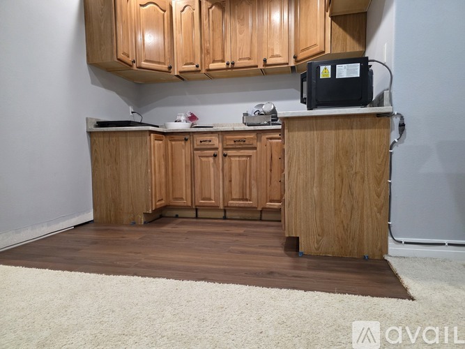 A kitchen with wooden cabinets and a white rug on the floor.