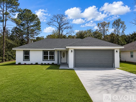 A white house with a grey garage door is for sale.